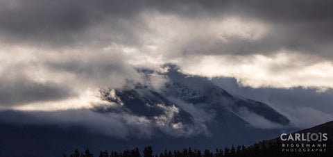fogs covering rocky mountain under cloudy sky during daytime